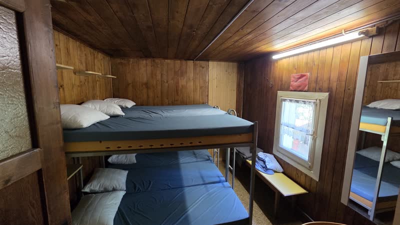 Zimmer 1 mit Kajütenbetten aus Holz, blauen Matratzen und Fenster zum Wald