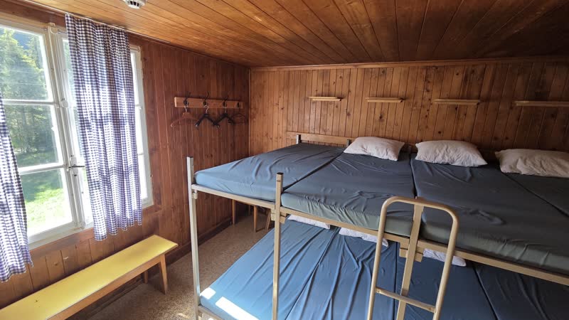 Zimmer 2 mit breiten Etagenbetten, Bank unter dem Fenster und karierten Vorhängen